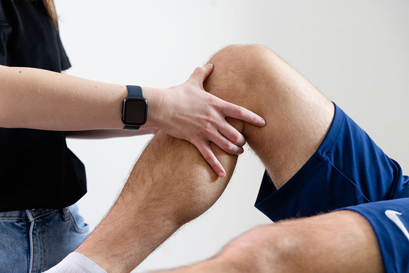 Fysiotherapeut voelt aan knie van patient